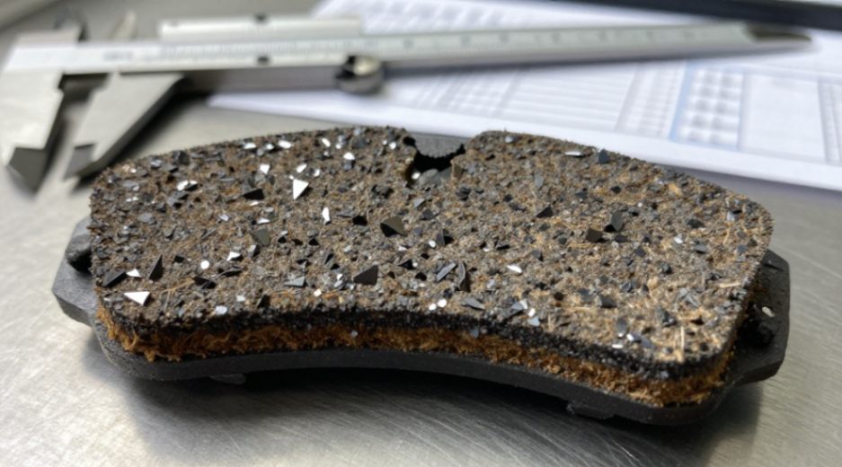 Silicon carbide powder (dark, angular particles) reinforces the brake pad matrix for superior wear resistance.